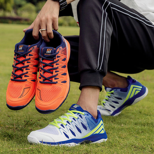 Man in sporty track pants holding orange athletic sneakers, wearing blue and white running shoes on grass, FashionRay style