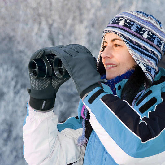 Woman in winter jacket and knit hat using binoculars outdoors, FashionRay cozy winter style