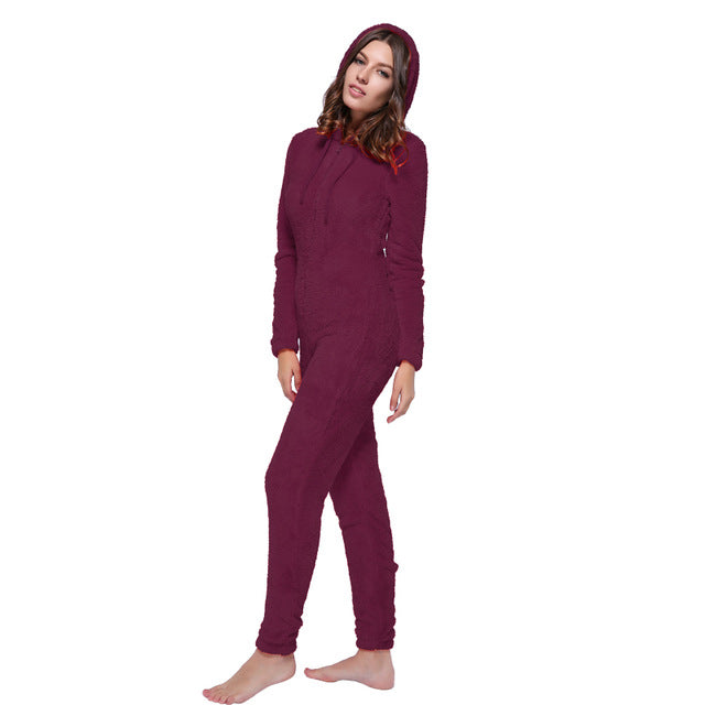 Woman wearing a cozy maroon hooded onesie from FashionRay, barefoot on white background