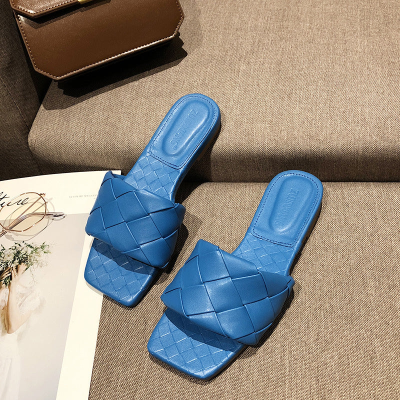 Blue woven slide sandals on a beige couch, stylish women's footwear at FashionRay