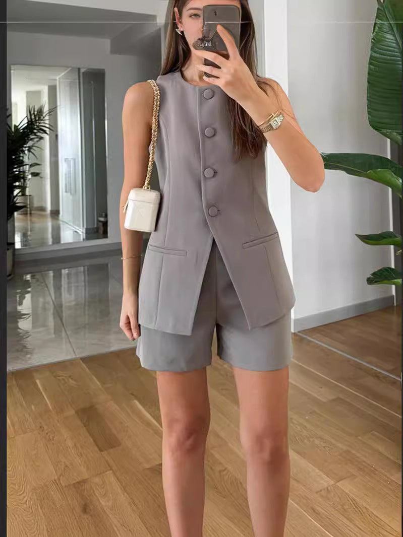 Woman wearing a sleeveless gray vest and shorts set, holding white purse, FashionRay style