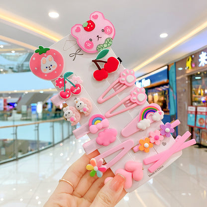 Set of cute pink hair clips with bear, bunny, flower, cherry, and rainbow designs held in a mall