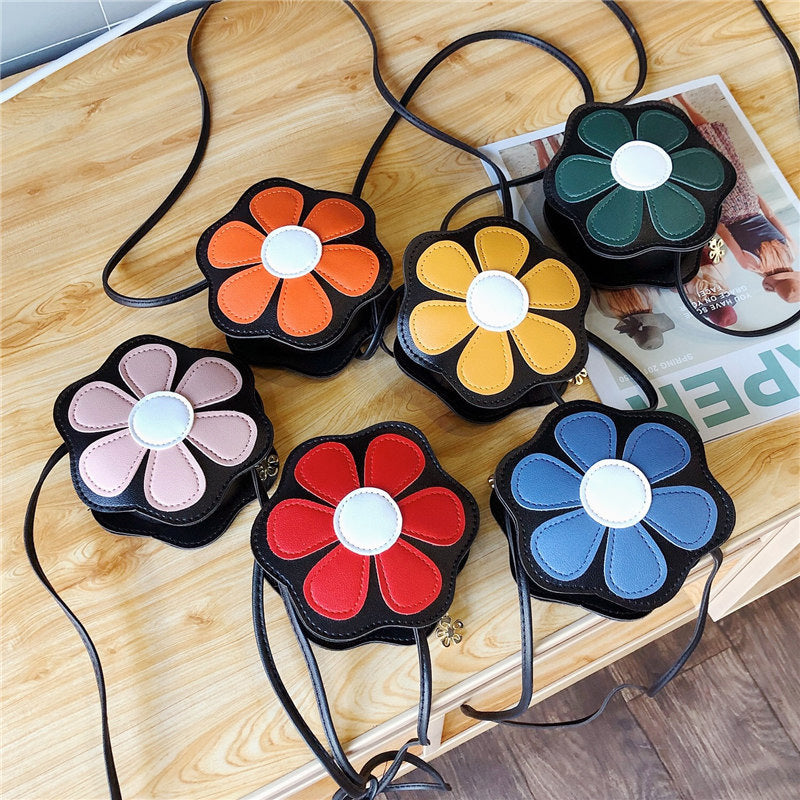 Colorful flower-shaped crossbody bags from FashionRay on a wooden table.