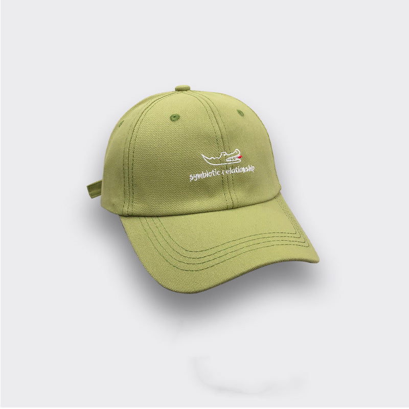 Light green baseball cap with embroidered crocodile and 'symbiotic relationship' text, FashionRay