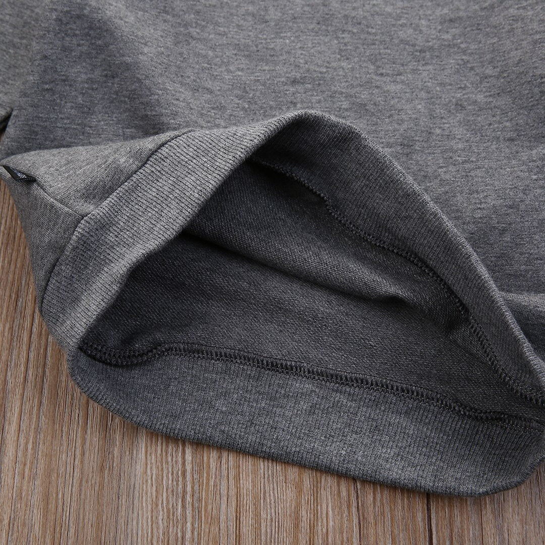 Close-up of a gray knit FashionRay sweatshirt hem on wood surface, showcasing soft fabric