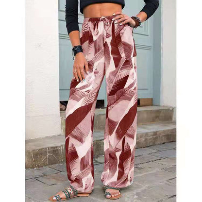 Woman wearing high-waisted, wide-leg tropical print pants in red and pink, styled for FashionRay.