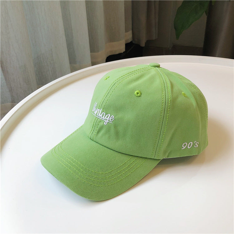 Light green vintage 90s embroidered baseball cap on white table, FashionRay trendy accessory