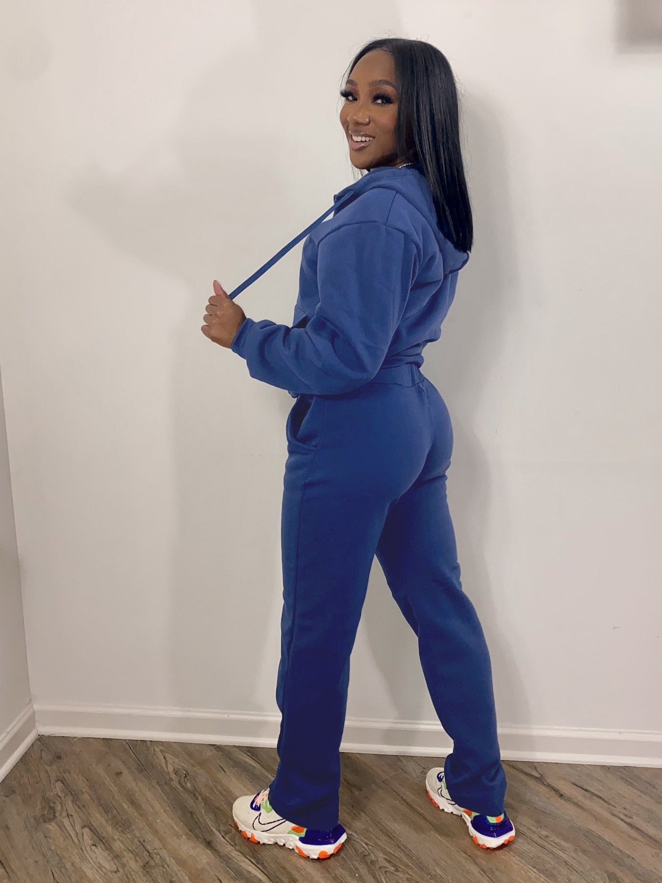 Woman in blue sweatsuit and colorful sneakers posing indoors at FashionRay