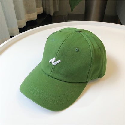 Trendy green baseball cap with white embroidered logo on a white table, FashionRay style