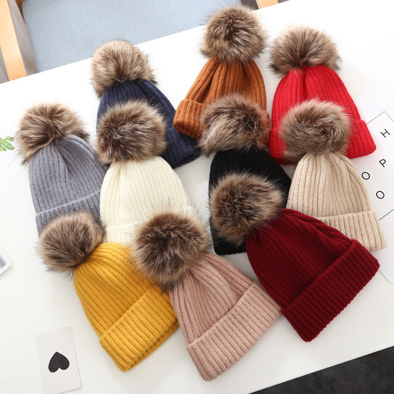 Assorted ribbed knit beanies with faux fur pom-poms in various colors on white table, FashionRay