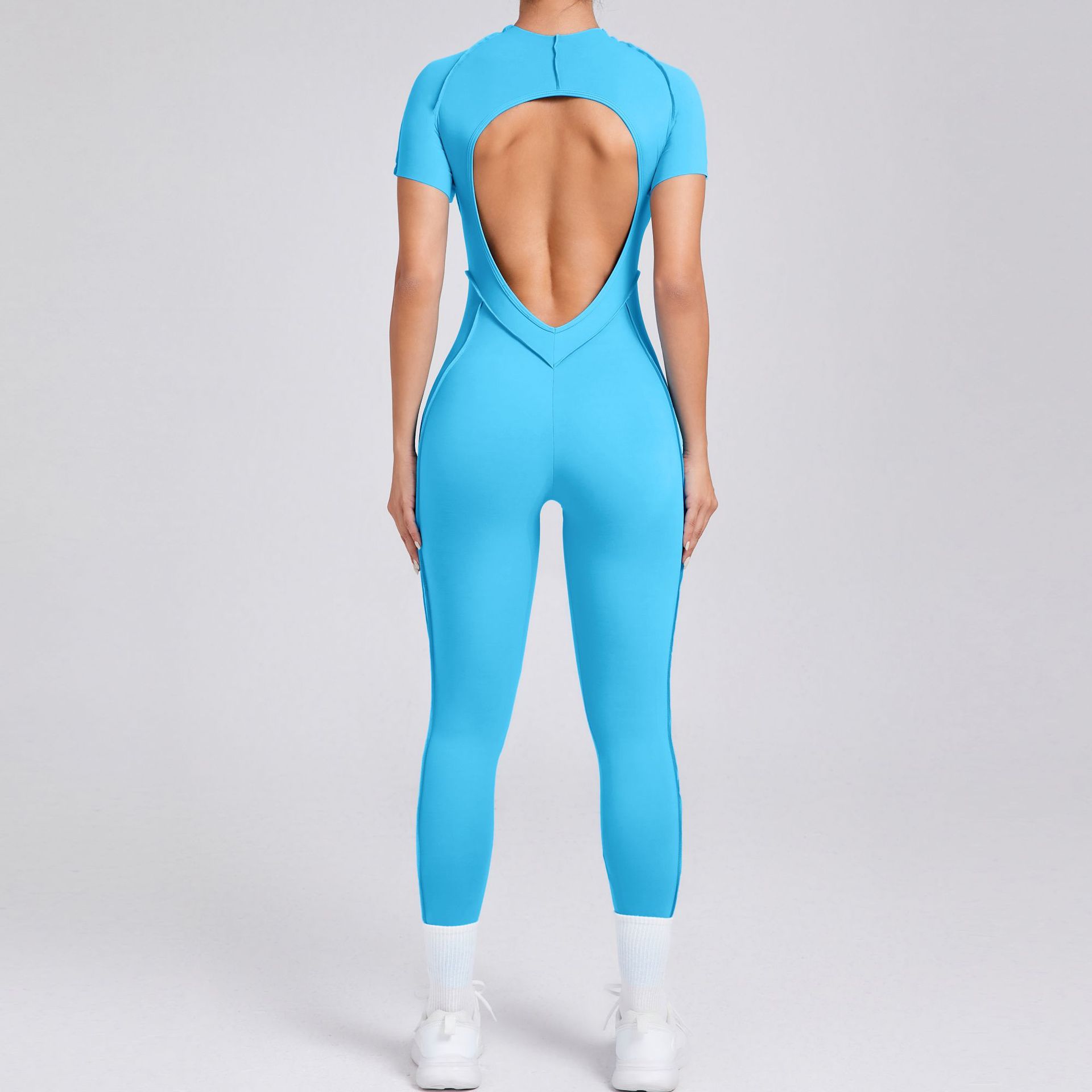 Woman in bright blue open-back jumpsuit, sporty style, FashionRay trendy activewear
