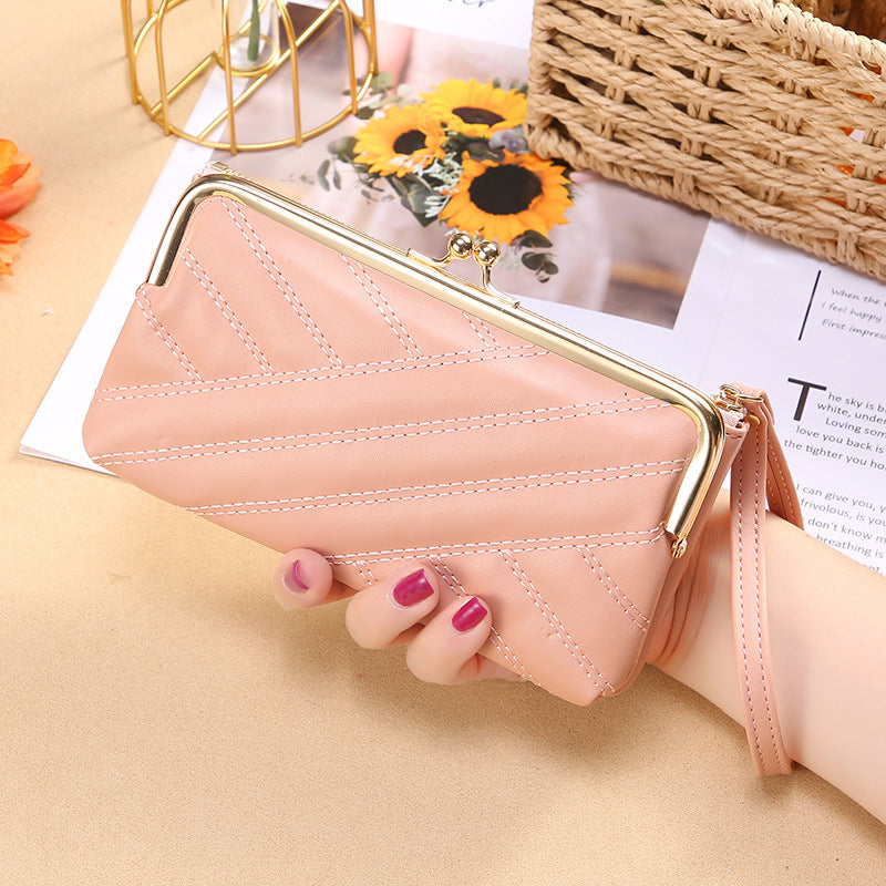 FashionRay pink quilted wallet clutch with wrist strap, held by hand, sunflowers in background