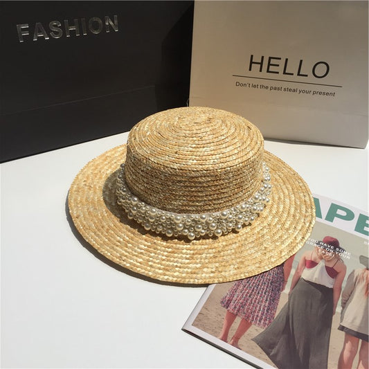 Woven straw sun hat with pearl trim, stylish accessory from FashionRay on display table