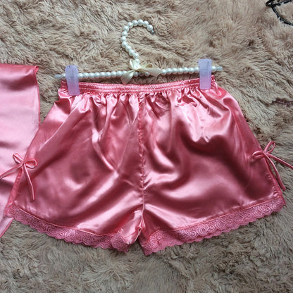 Pink satin pajama shorts with lace trim and ribbon bows on a fluffy beige rug, FashionRay