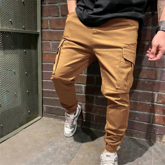 FashionRay men's tan cargo jogger pants with pockets, styled with sneakers against a brick wall.