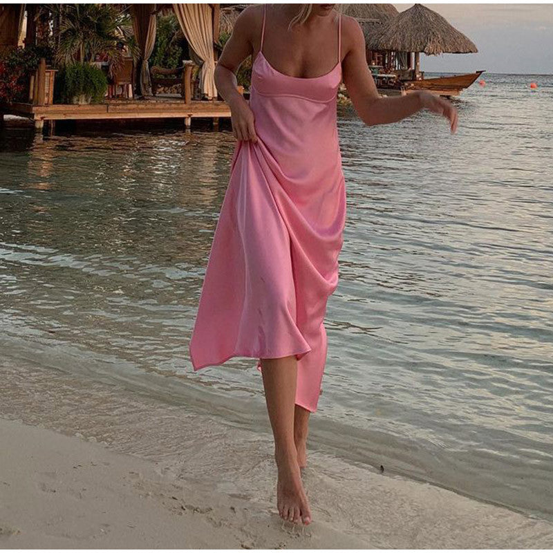 Woman in pink satin slip dress walking by the beach, tropical resort backdrop, FashionRay style