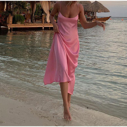 Woman in pink satin slip dress walking by the beach, tropical resort backdrop, FashionRay style