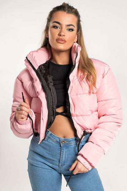 Woman in a pink puffer jacket, black crop top, and blue jeans, FashionRay trendy style