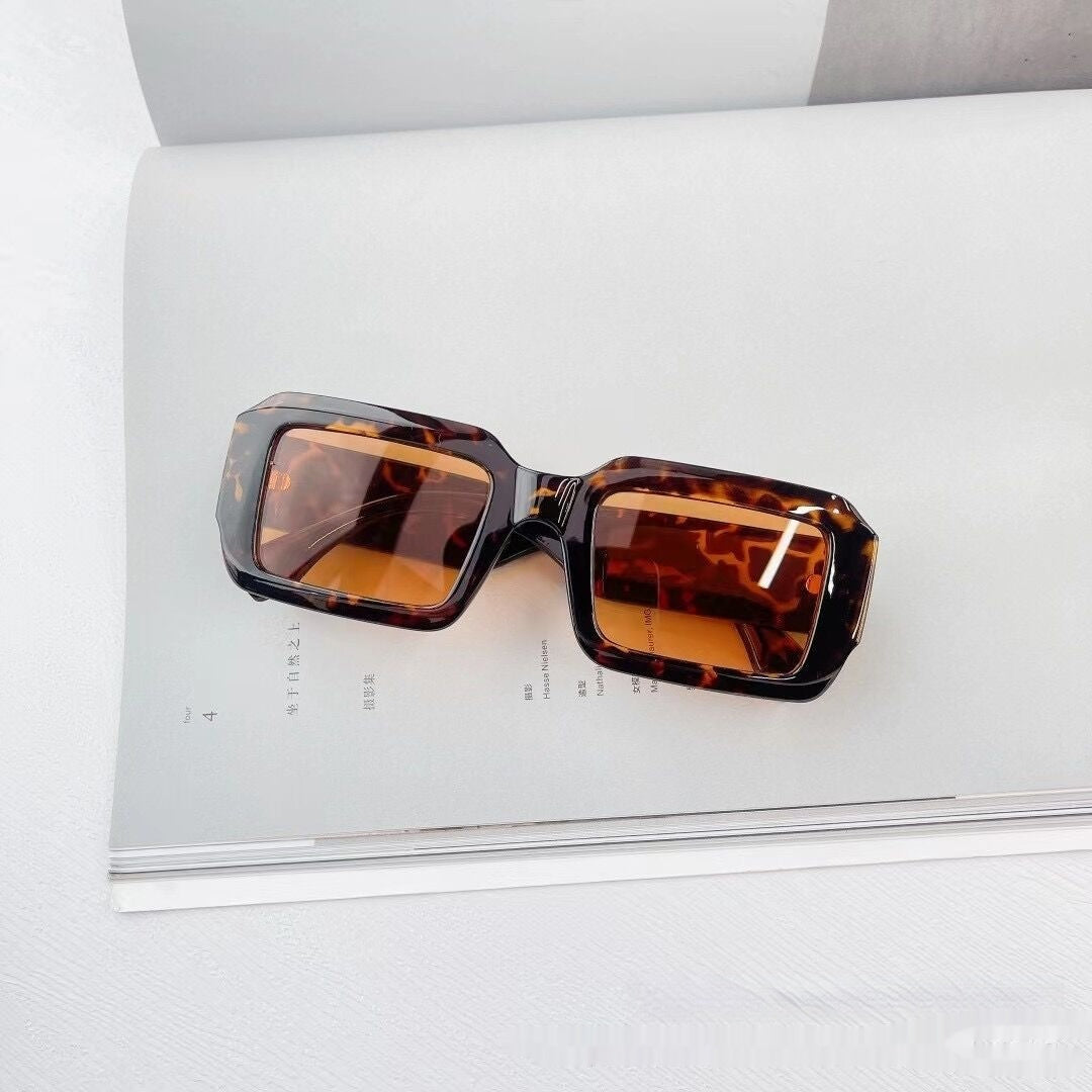 Tortoiseshell square sunglasses with brown lenses on an open magazine, FashionRay style
