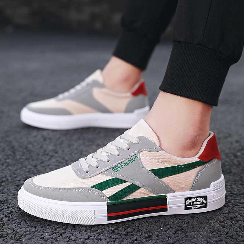Trendy beige and grey sneakers with green stripes and red heel from FashionRay on asphalt