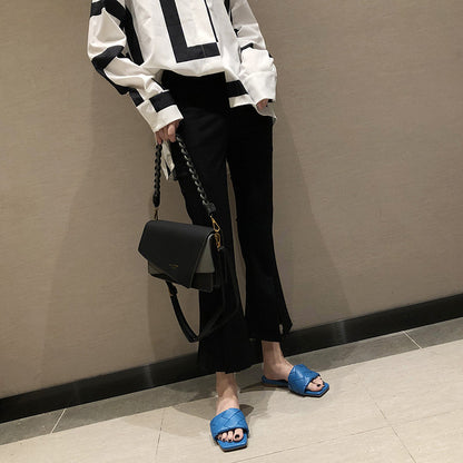 Trendy black pants, oversized graphic shirt, blue sandals, and black handbag from FashionRay