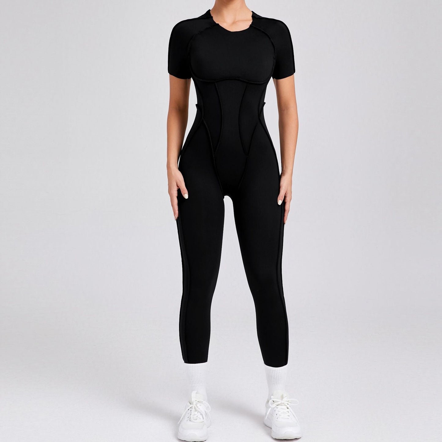 Woman wearing a fitted black jumpsuit and white sneakers, FashionRay trendy activewear