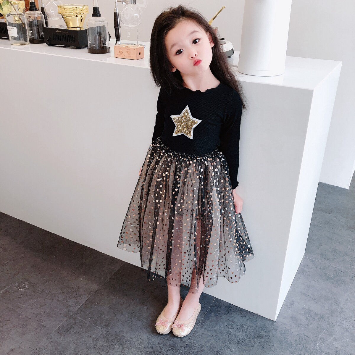 Girl in a black star dress with tulle skirt and gold flats, stylish FashionRay kids outfit