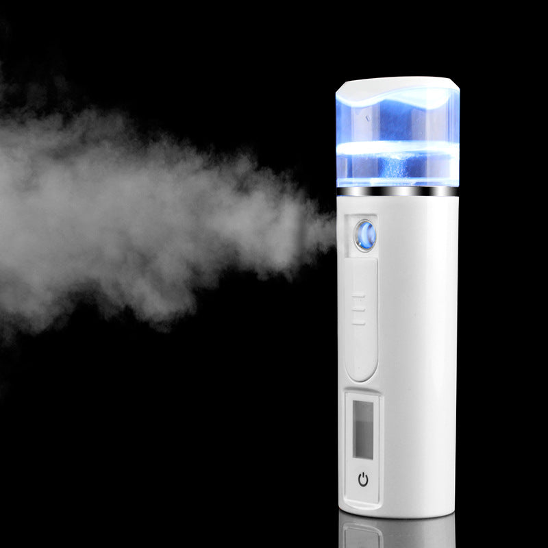 White portable facial mist sprayer with LED light on, emitting visible mist, on black background