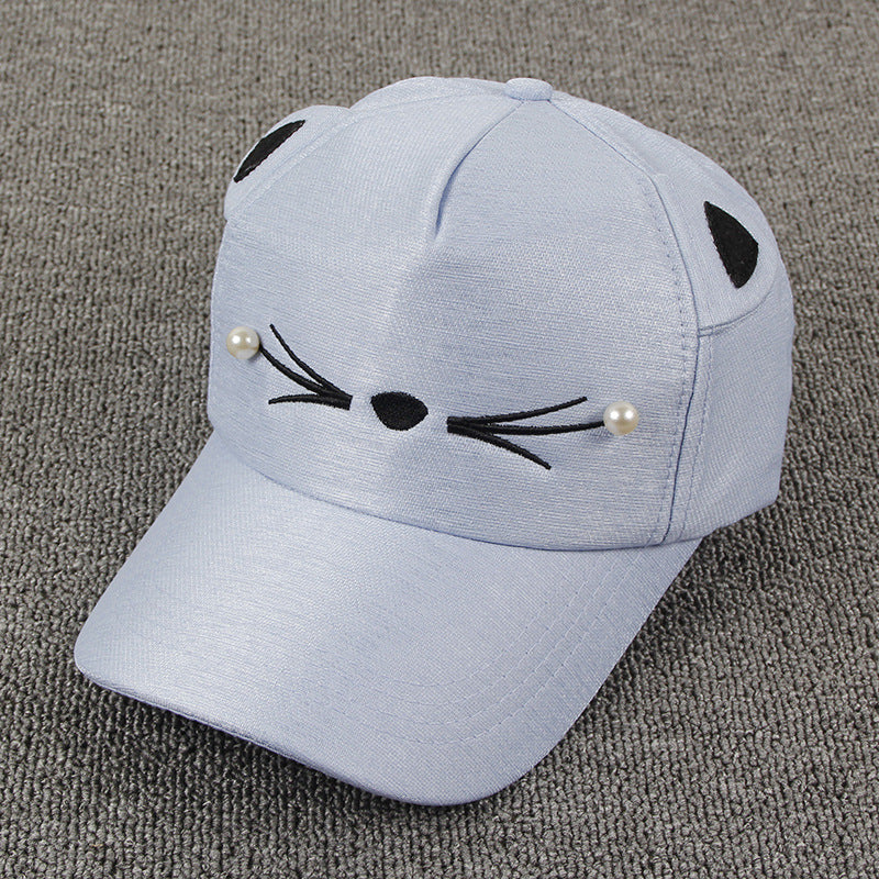 Light blue cat ear cap with embroidered whiskers and pearl accents on gray background