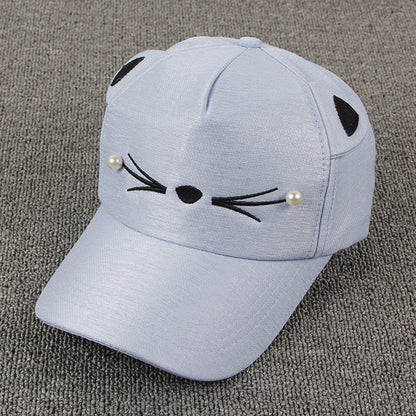 Light blue cat ear cap with embroidered whiskers and pearl accents on gray background