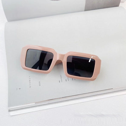 Trendy square pink sunglasses with black lenses on open magazine, FashionRay style accessory