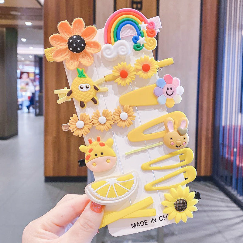 Cute yellow hair clips set with sunflowers, rainbow, and animal designs held in hand at FashionRay