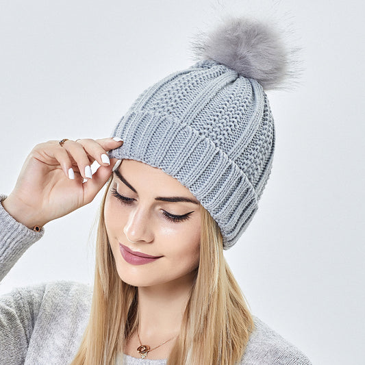 Woman wearing a light grey knit beanie with faux fur pom-pom, FashionRay style