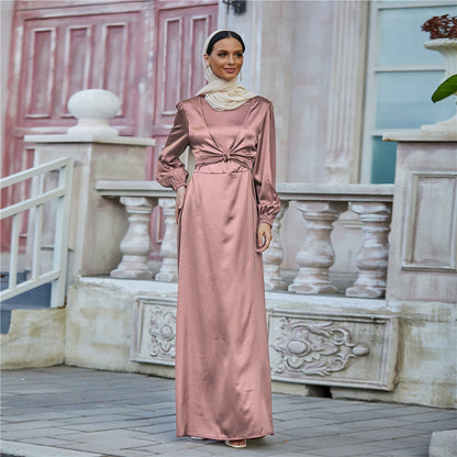 Woman in a long satin rose pink dress with cream headscarf, outside elegant building, FashionRay