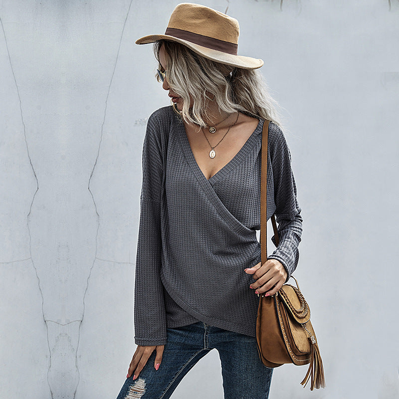 Woman in trendy waffle knit gray wrap top, ripped jeans, tan hat, and crossbody bag, FashionRay style