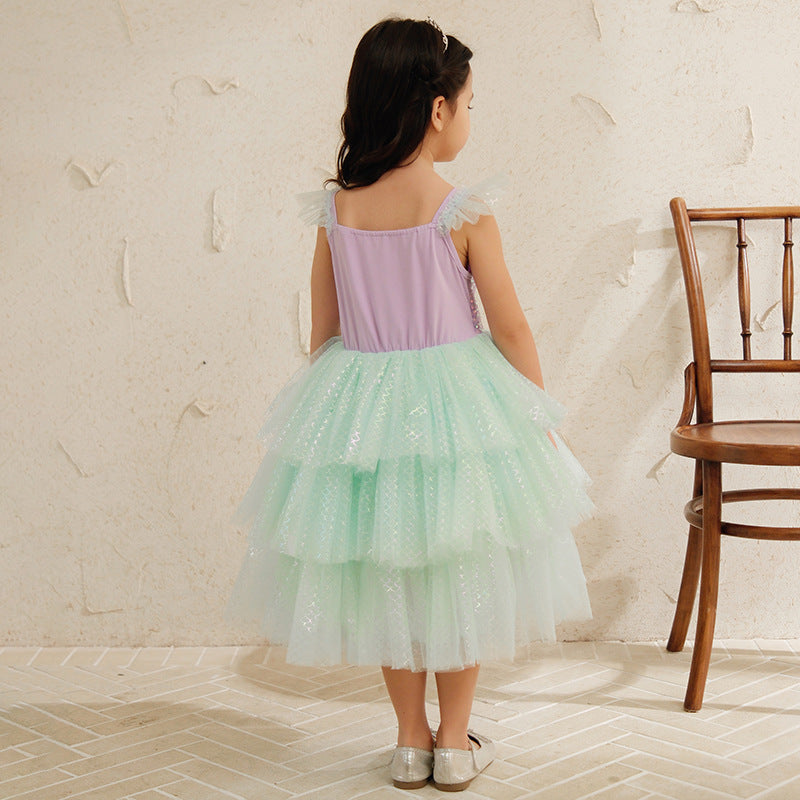 Girl in pastel tiered tulle dress stands indoors near wooden chair, FashionRay kids fashion