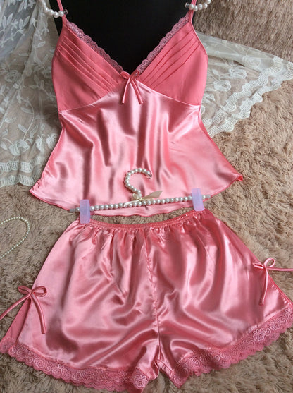 Pink satin pajama set with lace trim and pearl straps, displayed on soft fabric at FashionRay
