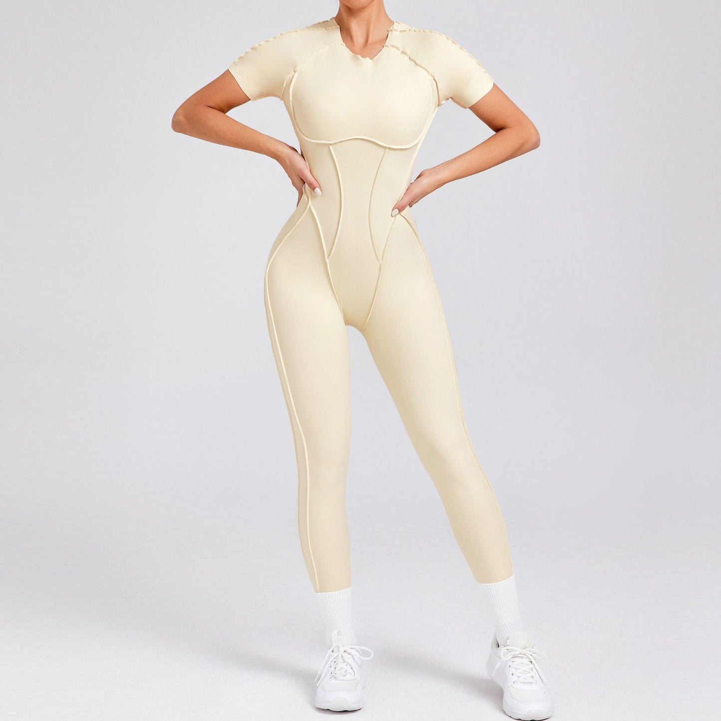 Woman modeling beige seamless jumpsuit with contour stitching from FashionRay, white sneakers