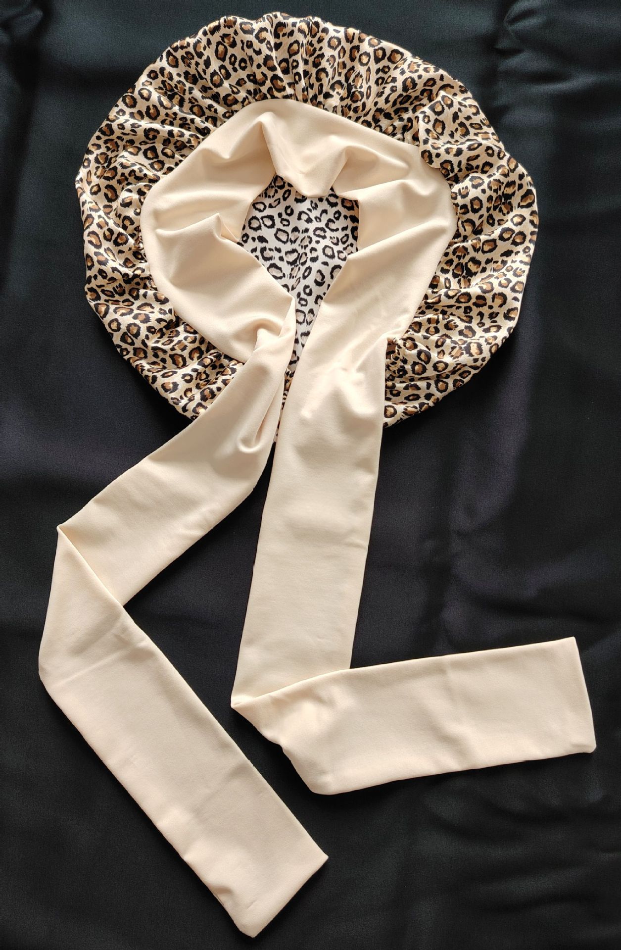 Leopard print satin bonnet with beige tie straps on black fabric, FashionRay accessory