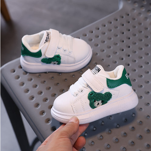 White and green toddler sneakers with bear design on perforated gray bench at FashionRay