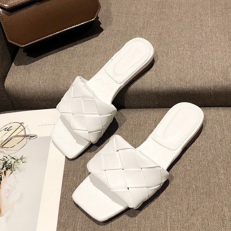 White woven slide sandals on a beige sofa, stylish women's footwear at FashionRay