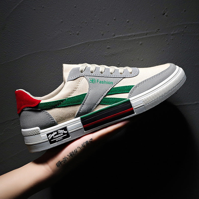 FashionRay trendy sneaker with green stripes, gray and red accents, held against a dark wall