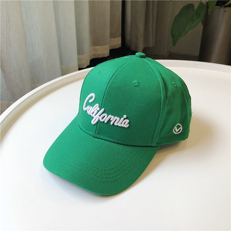 Green California embroidered baseball cap on white table, trendy streetwear FashionRay
