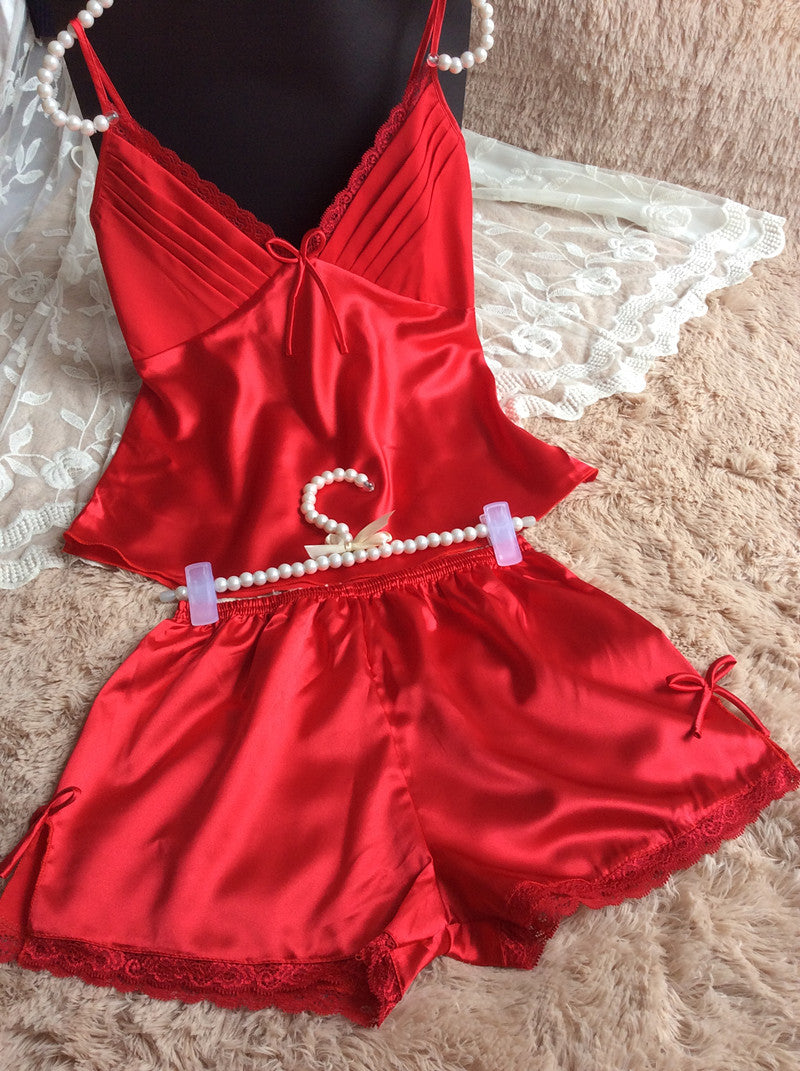Satin red camisole and shorts pajama set with lace details on a plush surface, FashionRay