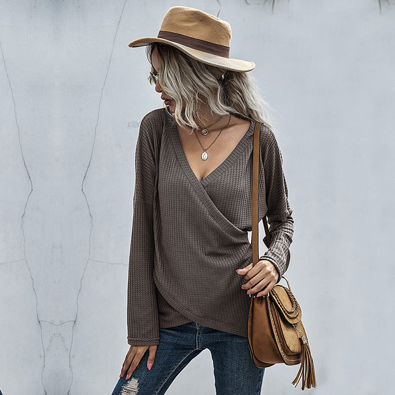 Woman in a taupe wrap sweater, distressed jeans, tan hat, and crossbody bag, fashion style