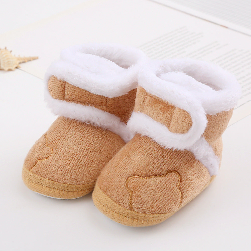 Fuzzy tan baby booties with white lining and bear face detail on FashionRay