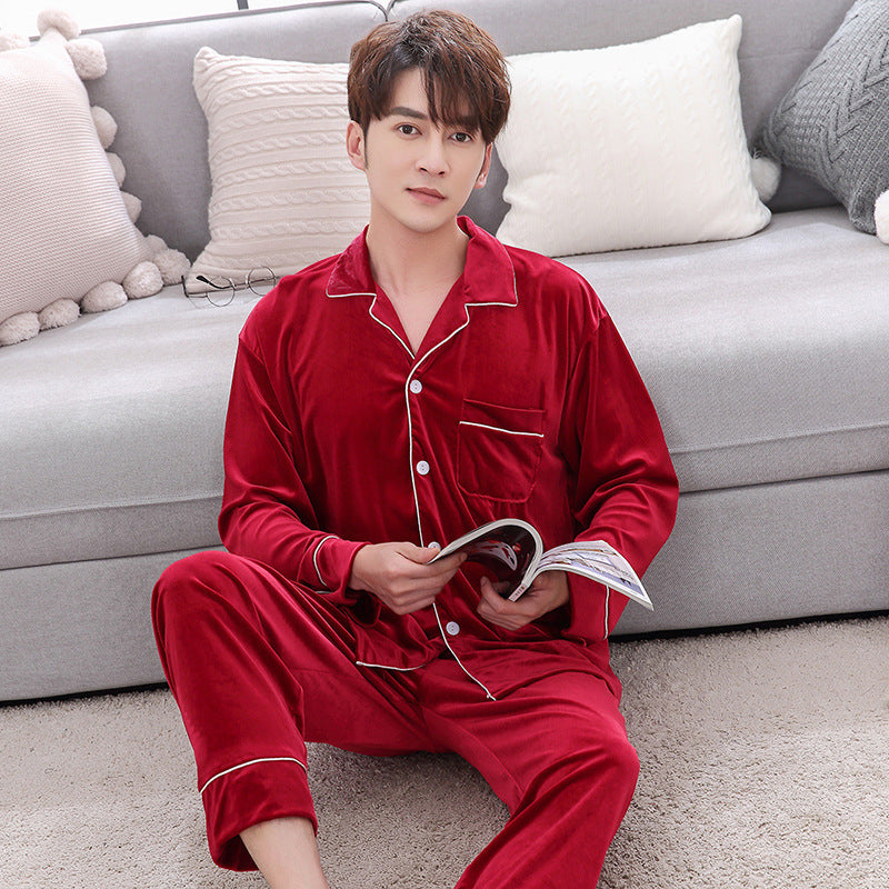 Man in red velvet pajamas sitting on carpet near sofa, reading magazine, cozy home fashion