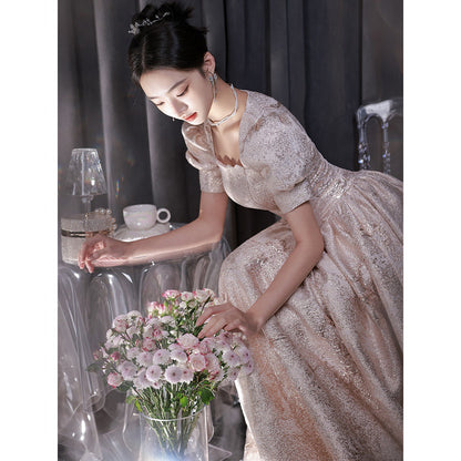 Elegant woman in shimmering gown arranging pink flowers in a chic, modern setting, FashionRay style