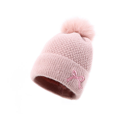Soft pink knit beanie with pom-pom and bow, cozy winter hat from FashionRay