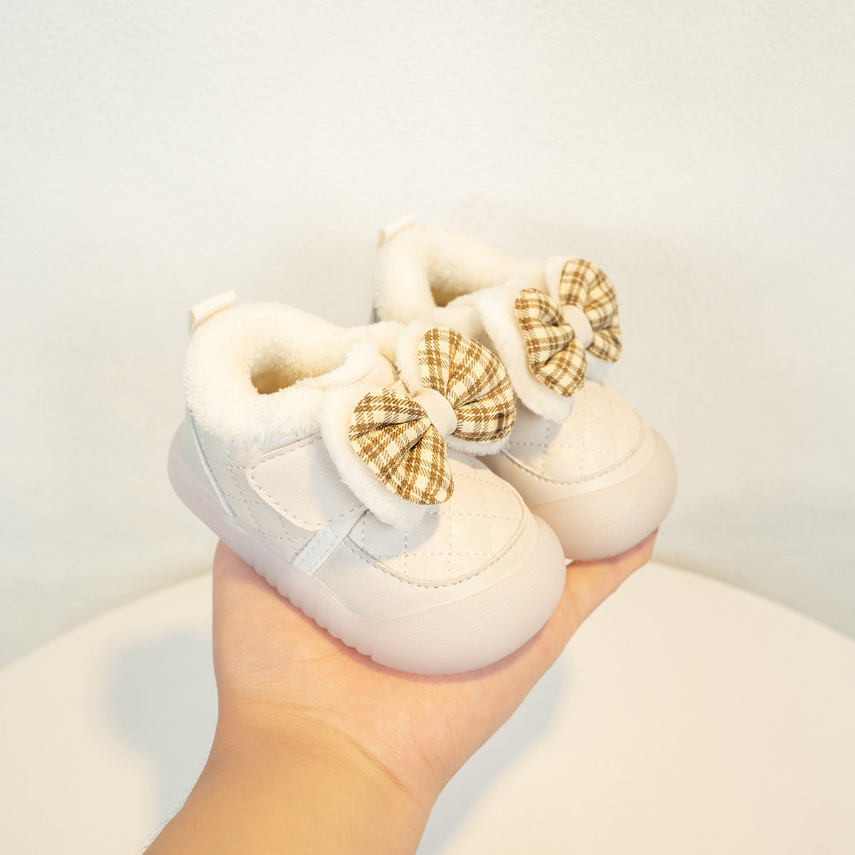 FashionRay cozy baby shoes with plaid bows and soft fur lining, held in hand